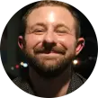 Grinning Caucasian man with auburn facial hair.